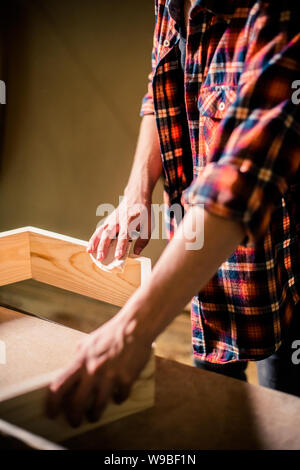 Bel giovane falegname la lavorazione del legno nel suo laboratorio di falegnameria, falegname titolare di azienda Foto Stock