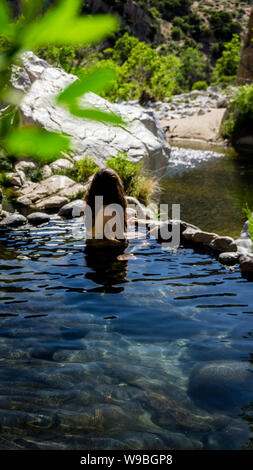 Modello femminile rilassante nella piscina naturale a deep creek hot springs in California, Stati Uniti d'America Foto Stock