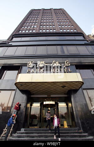 Un lavoratore cinese mette i tocchi finali sul Park Hotel dopo un volto a sollevare in Cina a Shanghai, 6 gennaio 2010. Il Park Hotel, l'edificio più alto Foto Stock