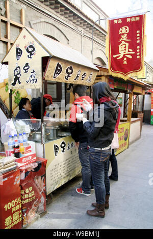 Locali residenti cinesi acquistare stinky tofu, un tradizionale spuntino cinese, in corrispondenza di una via denominata booth, il tofu puzzolente e della nazionale di calcio, su un foo Foto Stock