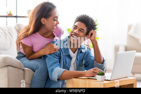 Felice coppia nero lavorando insieme sul portatile a casa. Foto Stock