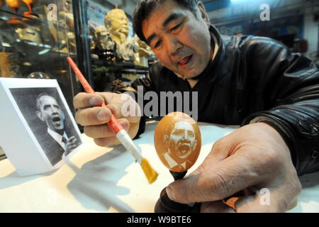 Folk Cinese scultore Kang Yongguo spazzole il guscio di un uovo di gallina con il ritratto di U.S. Il presidente Barack Obama nel suo studio di Shenyang city, Foto Stock