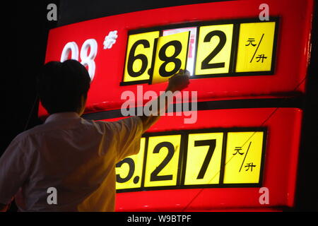 Un cinese alla stazione di servizio lavoratore aggiorna i prezzi del carburante in corrispondenza di una stazione di rifornimento di Sinopec a Pechino, Cina, lunedì, 1 giugno 2009. La Cina è aumentato il prezzo del carburante Foto Stock