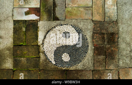 Ying e Yang segno su un weathered muro di mattoni Foto Stock