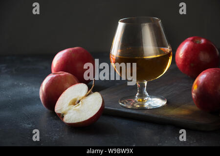 Vetro con calvados brandy e mele rosse su nero. Close up. Foto Stock