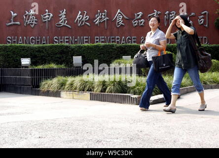 Due le donne cinesi a piedi passato l'impianto di imbottigliamento di Shanghai Shen-Mei bevande e cibo Co., Ltd., in parte di proprietà di Coca Cola in Cina a Shanghai, 11 set Foto Stock