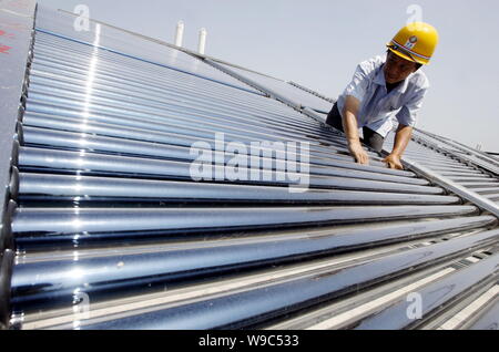 --FILE--un lavoratore cinese installa energia solare di acqua calda sulla parte superiore di un edificio di Chongqing Cina, 29 luglio 2009. Ai legislatori cinesi sono considerin Foto Stock