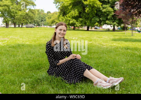 Sana ragazza sorridente nell'erba verde. Bella giovane donna all'esterno. Foto Stock