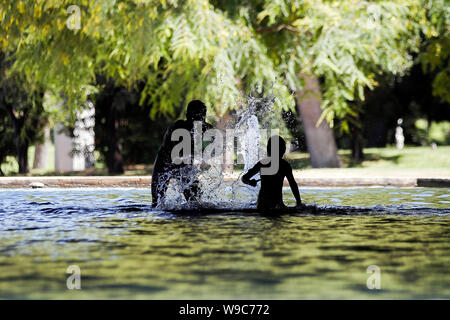 Un uomo e sua figlia di trovare sollievo in una fontana di Turia's Garden a Valencia, durante una ondata di caldo. Foto Stock