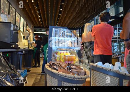 All'interno di Belgrado di Starbucks Cafe in Serbia, con persone in attesa in linea accanto a un banco espositore refrigerato. Foto Stock