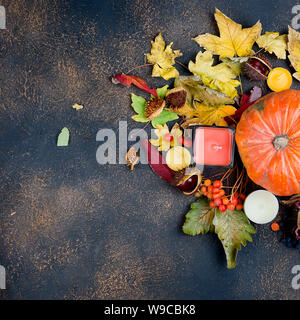 La zucca, candela, castagno nel guscio in un bicchiere e autunnali caduto foglie di acero su sfondo scuro, rientrano ancora in vita, concetto di autunno Foto Stock