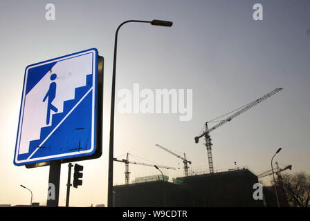 Un segno per andare verso il basso per un passaggio sotterraneo è visibile nella parte anteriore di un progetto immobiliare in costruzione a Pechino, in Cina, il 21 dicembre 2009. Mento Foto Stock