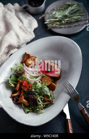 Tagliata di manzo con verdure. Close-up, chiave di basso, uno sfondo grigio. Foto Stock