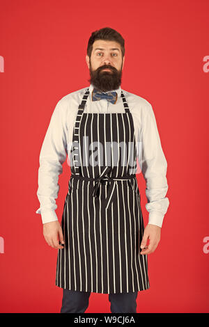 Io sono totalmente a vostro servizio. Un uomo servo. Uomo Barbuto che indossa la bib grembiule. L'uomo cook con barba e baffi in cucina il grembiule. Elegante uomo cameriere o barista. Foto Stock