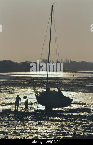 I marinai partecipando al loro yacht con la bassa marea. Porto di Chichester, West Sussex, in Inghilterra, Regno Unito Foto Stock