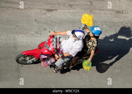 A Saigon, Vietnam, 18 dic. 2017, una donna in moto trasporta un fiore per le strade di Saigon. Foto Stock