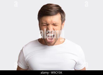 Ritratto di Emotional Man urlando furiosamente su sfondo bianco Foto Stock