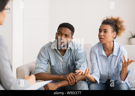 African American moglie parlando di giovane consigliere seduto accanto al marito Foto Stock