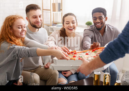 Happy amici prendendo fette di pizza calda dalla scatola Foto Stock