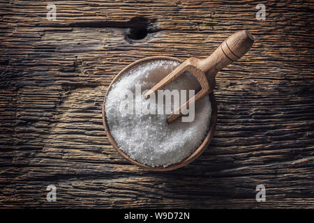 A GRANA GROSSA sale in una ciotola di legno con un mestolo su un vecchio tavolo in legno di quercia Foto Stock