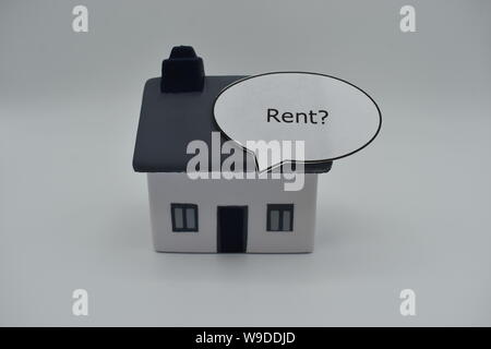 Un modello di casa con la parola 'affitto?" in un discorso bolla sul tetto. Foto Stock