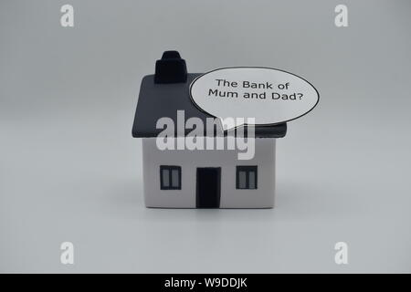 Un modello di casa con le parole "banca di mamma e papà?" in un discorso bolla sul tetto. Foto Stock