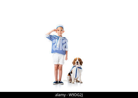 Lunghezza piena vista del bambino preschooler in costume da marinaio salutando con sorriso e cane beagle su bianco Foto Stock