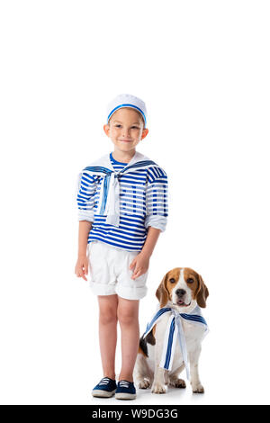 Lunghezza piena vista del sorridente preschooler bambino in costume da marinaio e cane beagle su bianco Foto Stock
