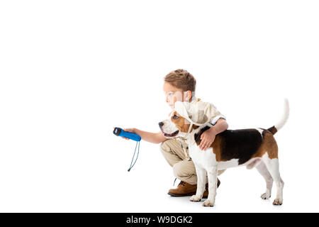 Sorridente explorer bambino tenendo la torcia elettrica e abbracciando il cane beagle in hat isolato su bianco Foto Stock