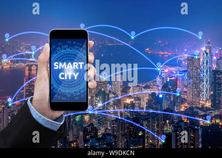 Le donne d'affari visualizza Smart city il collegamento con lo smartphone su smart city rete di comunicazione e di internet delle cose per la comunicazione in rete conce Foto Stock