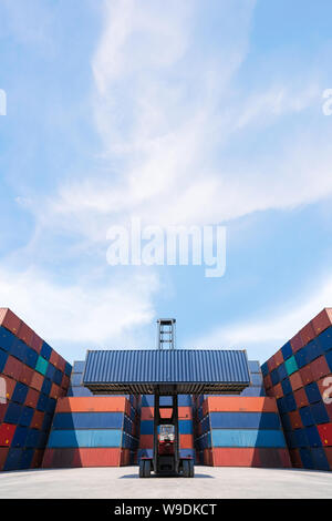 Carrello elevatore a forche di sollevamento del contenitore di carico in cantiere per la spedizione o la dock yard con il contenitore di carico pila in background per il concetto di spedizione. Foto Stock