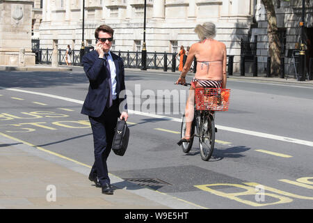 Westminster, Londra, UK, 13 agosto 2019. Un fedele di sole in un bikini e non molto altro, cicli giù Whitehall a Westminster. Dopo giorni di pioggia e temperature più basse, il clima caldo segna un cambiamento di benvenuto per i londinesi. Credito: Imageplotter/Alamy Live News Foto Stock