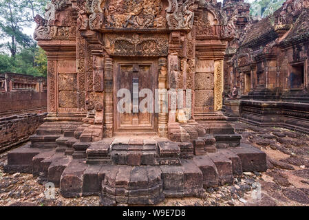 Porta cieca, ringhiere e devatas scavate nella pietra arenaria rossa pareti di Banteay Srei area del tempio di Angkor a Siem Reap, Cambogia Foto Stock