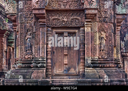 Porta cieca, ringhiere e devatas scavate nella pietra arenaria rossa pareti di Banteay Srei area del tempio di Angkor a Siem Reap, Cambogia Foto Stock