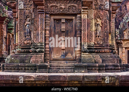 Porta cieca, ringhiere e devatas scavate nella pietra arenaria rossa pareti di Banteay Srei area del tempio di Angkor a Siem Reap, Cambogia Foto Stock