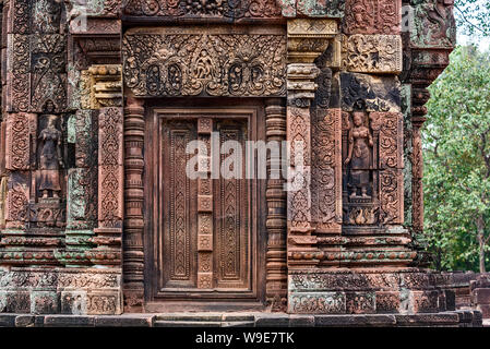 Porta cieca, ringhiere e devatas scavate nella pietra arenaria rossa pareti di Banteay Srei area del tempio di Angkor a Siem Reap, Cambogia Foto Stock