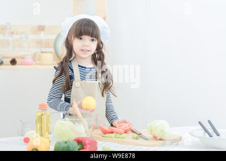 Ragazza carina preparare cibi sani insalata in camera con cucina.Foto design per la famiglia, i bambini e le persone felici concetto. Foto Stock