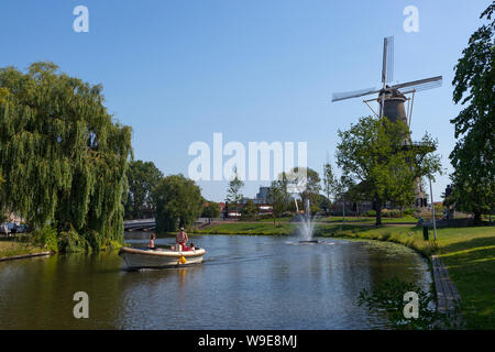 Leiden, Olanda - Luglio 26, 2019: la vela di una barca da diporto con la storica torre mill de Valk, Falcon, in background Foto Stock