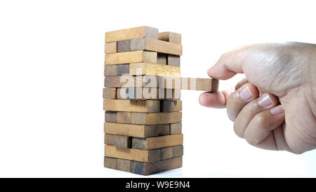 La torre da blocchi di legno e di mano d'uomo prendere un blocco. Il gioco dei dadi di close-up. Foto Stock