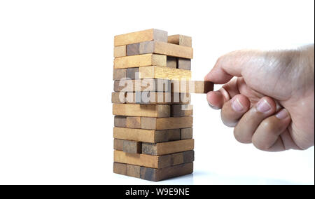 La torre da blocchi di legno e di mano d'uomo prendere un blocco. Il gioco dei dadi di close-up. Foto Stock