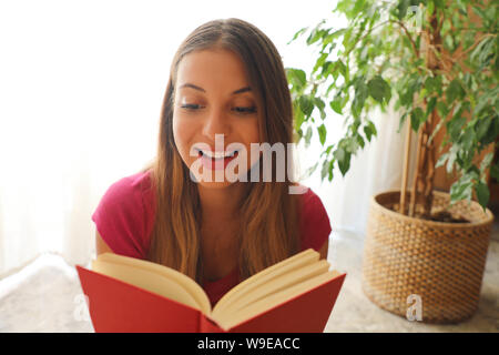 Giovane bella donna seduta e la lettura di un libro gode del resto Foto Stock