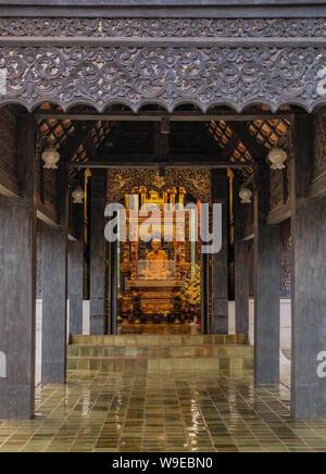 Chiang Mai, Thailandia - 25 dicembre 2017: dorato ed illuminata la scultura alla fine di un corridoio di legno Foto Stock