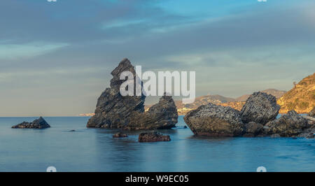 Nerja, Malaga, Spagna - 4 Febbraio 2019: Sunrise su una solitaria spiaggia con alcuni grandi massi sulla riva Foto Stock