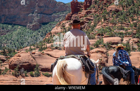 Sedona in Arizona Stati Uniti d'America. Maggio 25, 2019. Persone con cappelli da cowboy a cavallo vista posteriore sul terreno. Rosso Arancio il paesaggio del deserto, soleggiata giornata di primavera Foto Stock