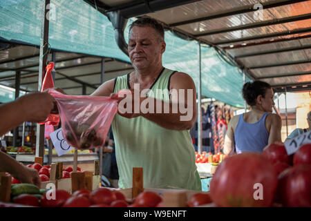 A Belgrado, in Serbia, 13 Luglio 2019: un venditore vegetali con i clienti a Zemun Mercato verde Foto Stock