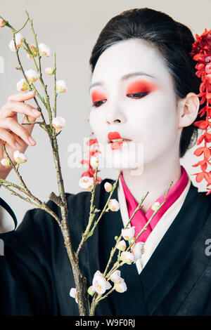 I rami degli alberi e bellissima geisha con il rosso e bianco specchio isolato su bianco Foto Stock