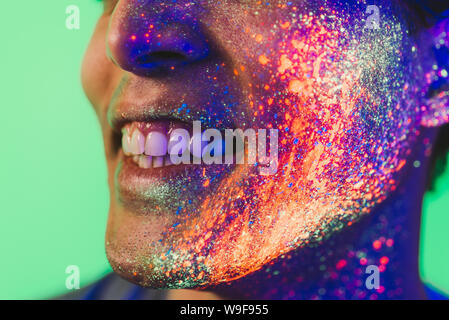 Bel ragazzo balli presso il rave party con dipinti fluorescenti sul suo volto Foto Stock
