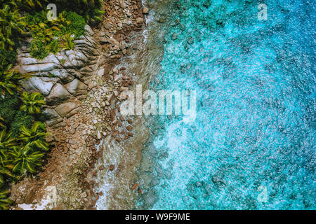Antenna fuco vista della costa tropicale, crystal clear oceano turchese acqua, bizzarre rocce di granito e palme di cocco. Concetto di viaggio Foto Stock