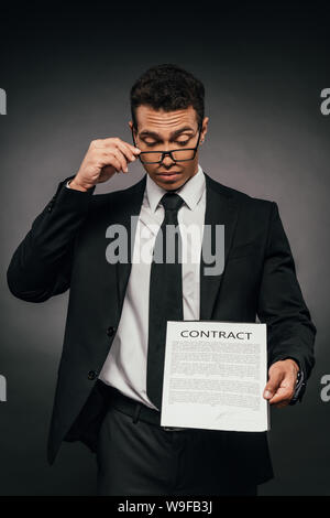 Sorpreso African American businessman mostra contratto su sfondo scuro Foto Stock