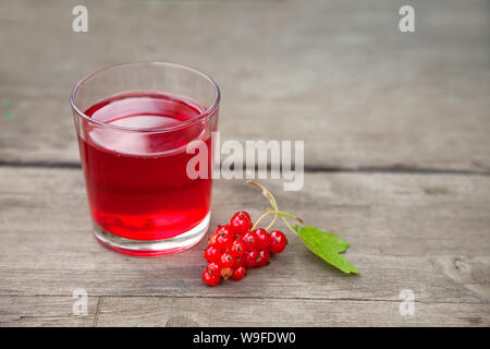Ramo di ribes rosso di bacche e di un bicchiere di vetro con un delizioso succo di bacca sul vecchio tavolo in legno Foto Stock